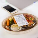 A packaged meal in a plastic container featuring fresh vegetables, ideal for healthy eating concepts.